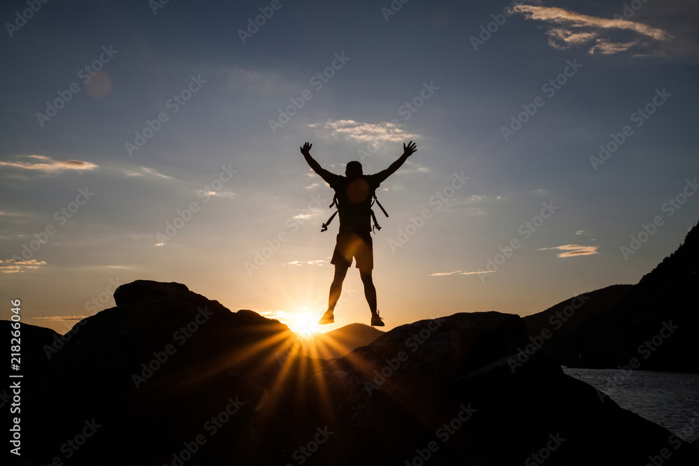 Man jumping on cliffs in sunset Man jumping on cliffs in sunset