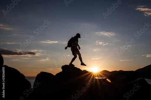 Man jumping on cliffs in sunset