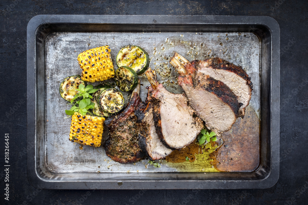 Traditionel barbecue veal back racks carree roast with corn and zucchini as top view on an old griddle Traditionel barbecue veal back racks carree roast with corn and zucchini as top view on an old griddle