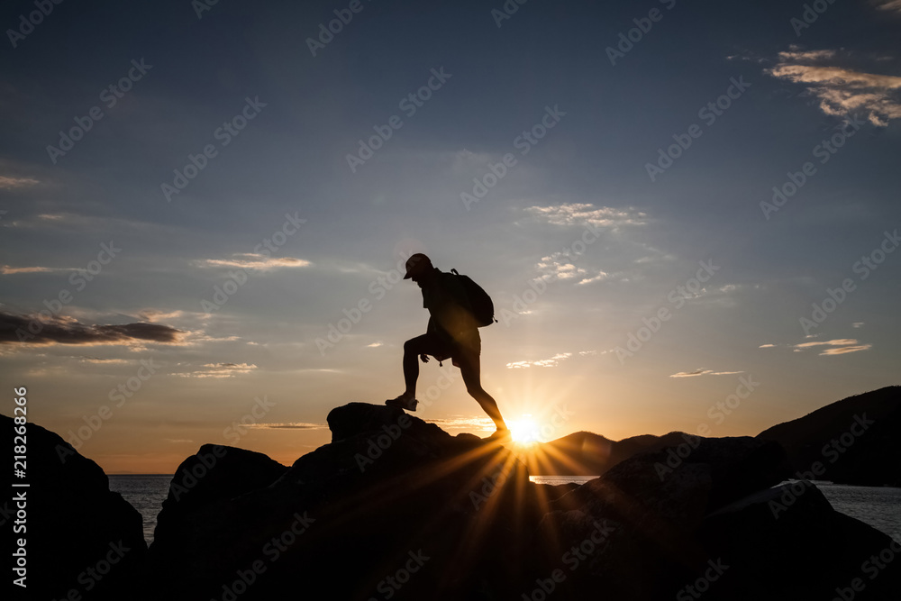 Man jumping on cliffs in sunset Man jumping on cliffs in sunset