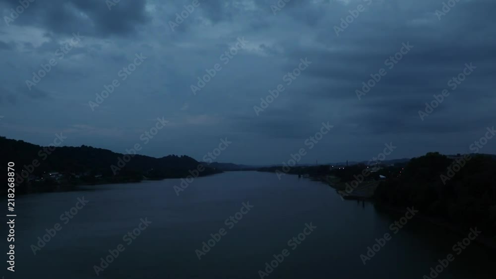 Slow moving clouds hang over river and hills at dusk blue hour Slow moving clouds hang over river and hills at dusk blue hour