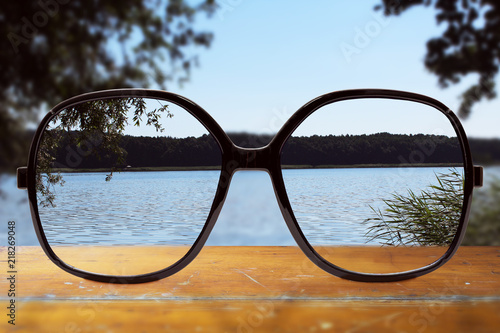 moderne Brille auf einem Holztisch vor einem See