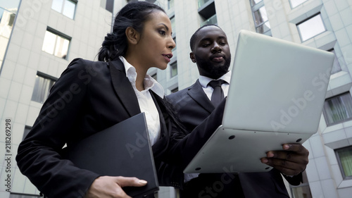 Fotografie Man and woman looking at laptop outside building, attorneys, brand new evidence