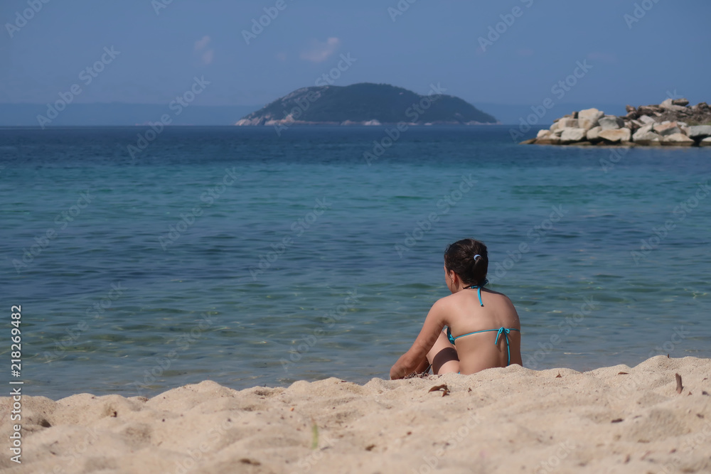 A girl on the beach looking at the sea