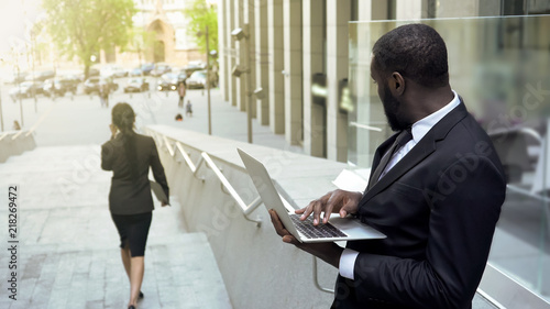 Distracted manager watching beautiful business lady in city street, affection