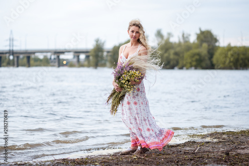 the girl sits on the river bank and dreams, ruu girl, blonde in a dress. photo