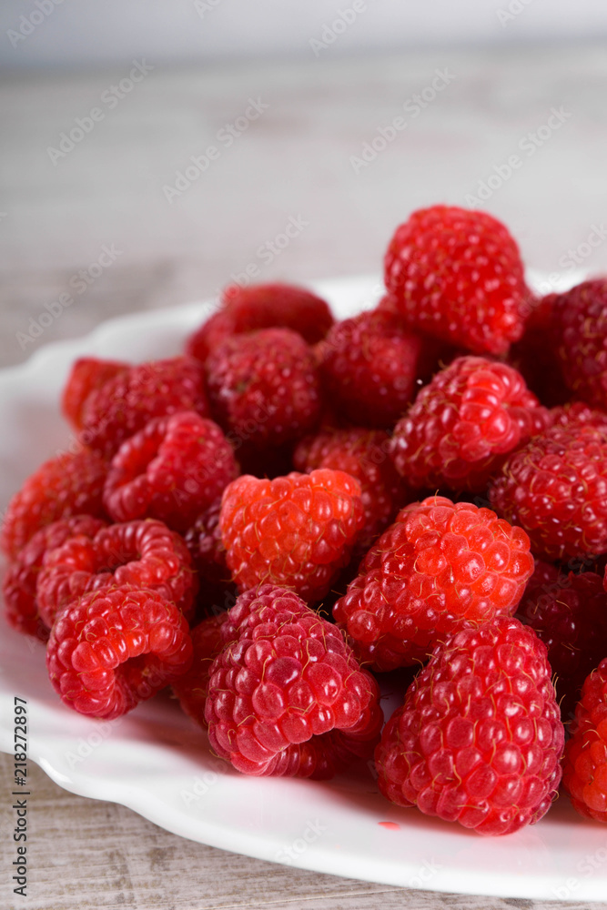 Red fresh raspberries on white rustic wood background. Plate with natural ripe organic berries.flat lay with copy space Red fresh raspberries on white rustic wood background. Plate with natural ripe organic berries.flat lay with copy space