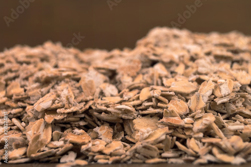 Oat flakes, poured in several layers on a wooden table, close-up with a small depth of field.