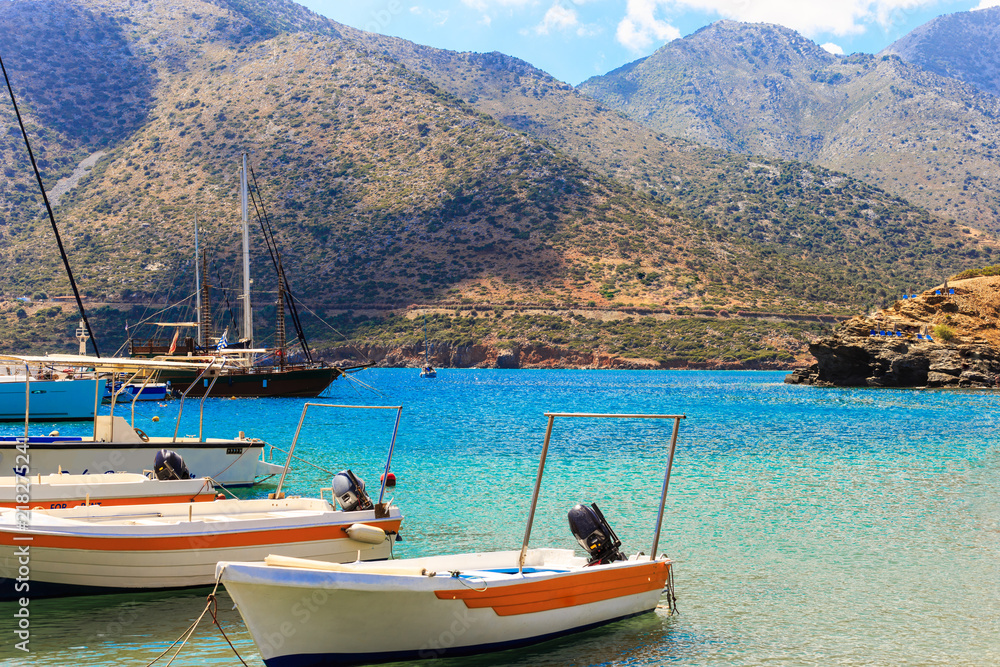 small fishing boats at pier in fishing village named Bali with mountains at background in Crete, Greece.