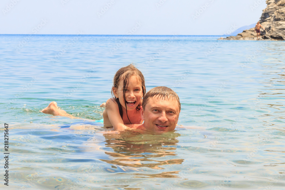 Happy family, active father with little adorable girl are swimming at the sea. Family vacation. Happy family, active father with little adorable girl are swimming at the sea. Family vacation.