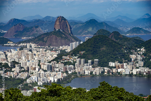Sugarloaf mountain in Rio de Janeiro seen from a high vantage point with the city lake in the foreground and the city of Niteroi in the background on the other side of the bay
