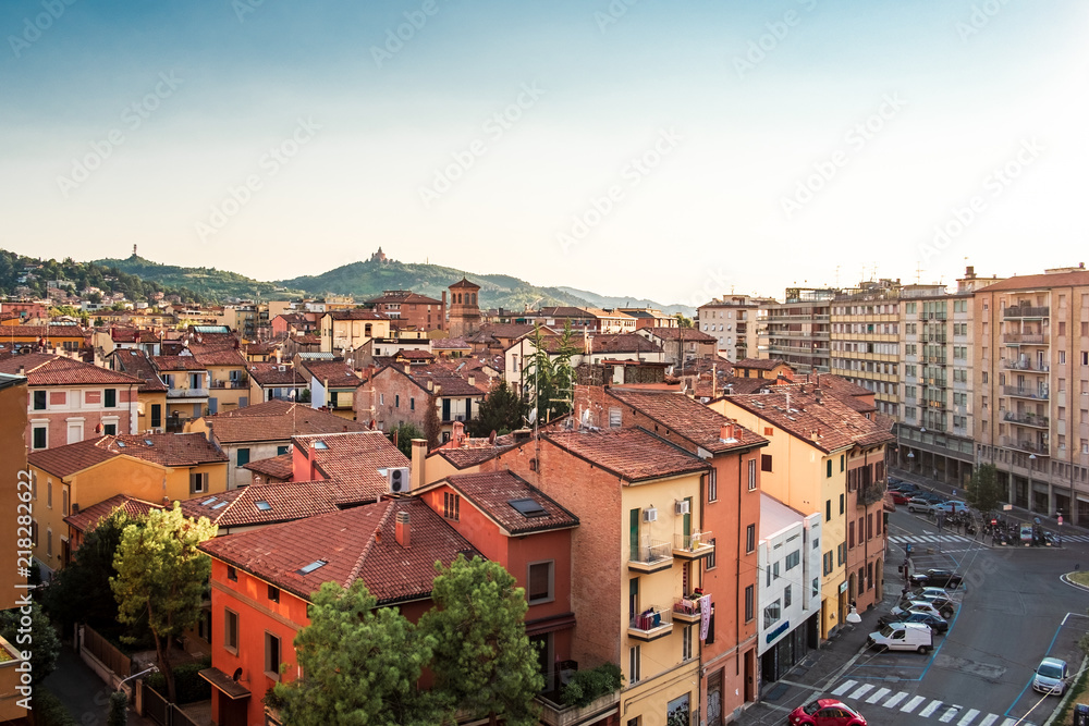 Bologna, Emilia Romagna, Italy. The roofs of city at sunset: Basilica of San Luca on the background.