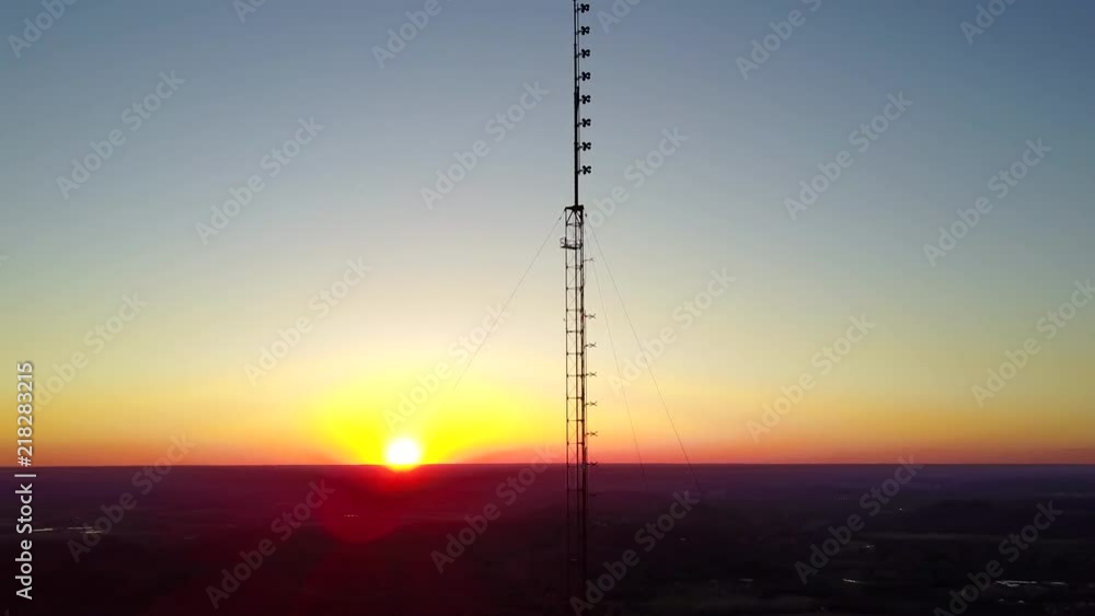 Aerial view of a tall broadcast tower ascension at sunset. Reversible
