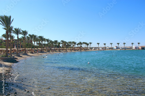 Tropical resort in Egypt. Palm trees sea sand beach. People rest on beach