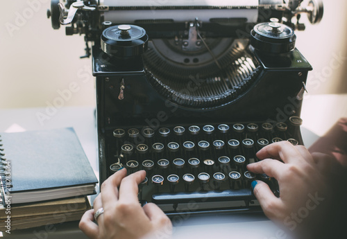 Woman's  hands writing on a vintage typewriter. Young woman writer at home, work on typewriter. photo