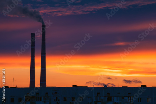 Colorful Magic Sunset. Roofs of city houses during sunrise. Dark smoke coming from the thermal power plant pipe.