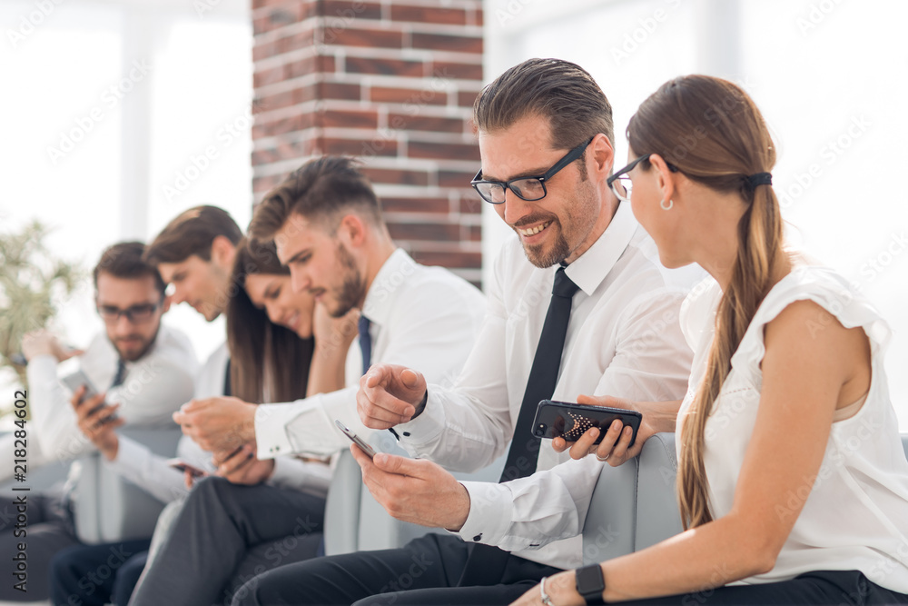 Obraz premium employees of the company using their smartphones sitting in the office lobby
