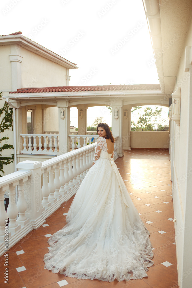 A beautiful bride in a white wedding dress is enjoying the moment against the backboard a beautiful arch in the sunset light. A fine mood, a great atmosphere. wedding concept
