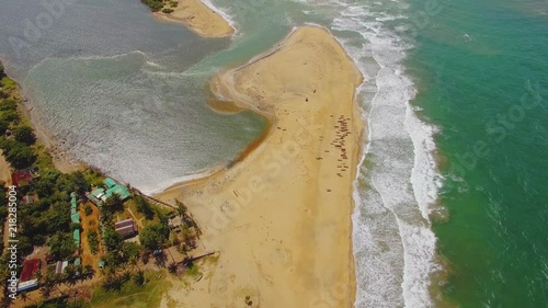 Aerial shot from Topview of waves at the beach with houses tilting up to reveal river and whole coastline. photo