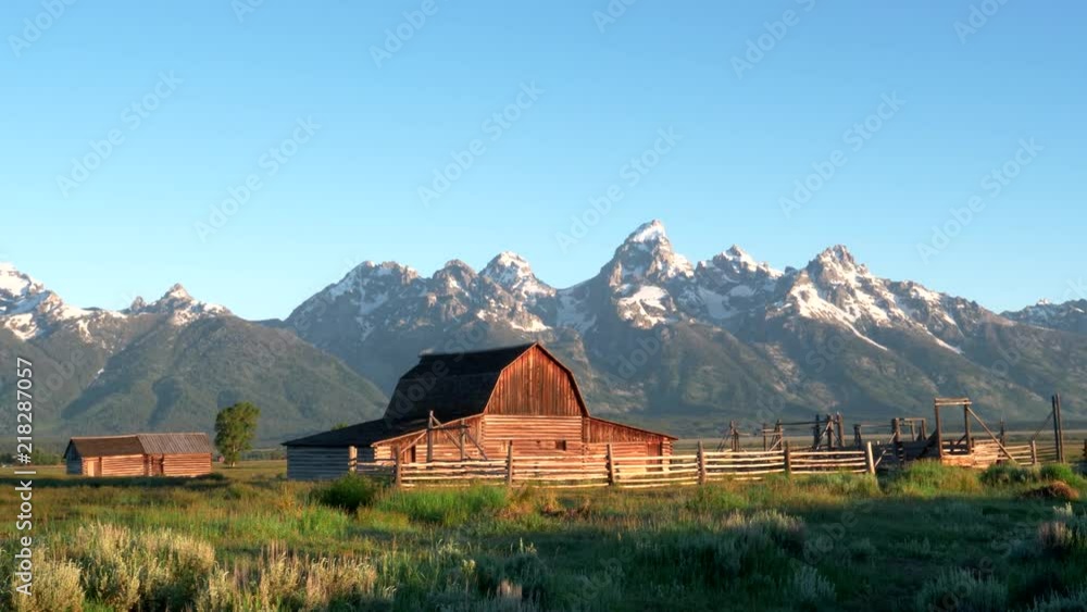 a sunrise wide panning shot of a mormon row barn and grand teton mountain in grand teton national park in the united states of america