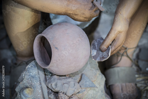 Life-sized sculpture of prehistoric man decorating clay bowl photo