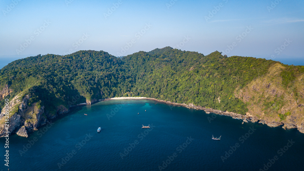 Aerial drone view of a beautiful tropical island with sheer, vertical cliffs and lush green jungle
