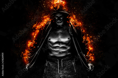 Strong young man with muscular body in burning black sport jacket with hood. Concept Power Body