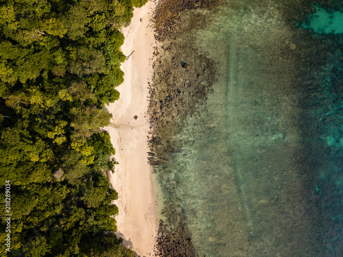 Aerial drone birds eye view of a beautiful tropical sandy beach, coral reef and lush, green jungle on a remote island