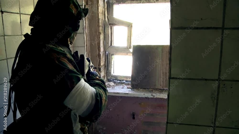 Soldier in military uniform with a weapon hiding in a destroyed house. Airsoft game for courageous men in Russia. Soldier in military uniform with a weapon hiding in a destroyed house. Airsoft game for courageous men in Russia.