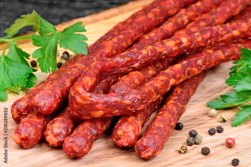 Sausages with peppercorns and parsley on cutting board Sausages with peppercorns and parsley on cutting board