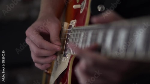 Man picking on the two bottom strings of a Les Paul style electric guitar - close up side shot of his strumming hand photo