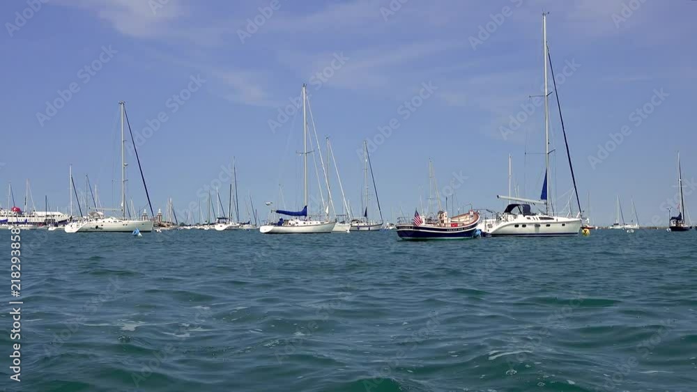 Panning shot of sailboat pulling out of Lake Michigan harbor in Chicago on a summer day. Panning shot of sailboat pulling out of Lake Michigan harbor in Chicago on a summer day.