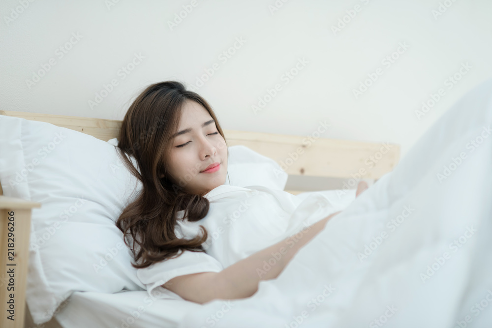 A beautiful young woman sleeping in bed. Happy morning. Portrait of a smiling pretty young woman relaxing in white bed. A beautiful young woman sleeping in bed. Happy morning. Portrait of a smiling pretty young woman relaxing in white bed.