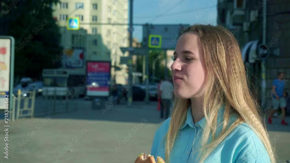 Close-up shot a young girl eating a hamburger on the street Close-up shot a young girl eating a hamburger on the street
