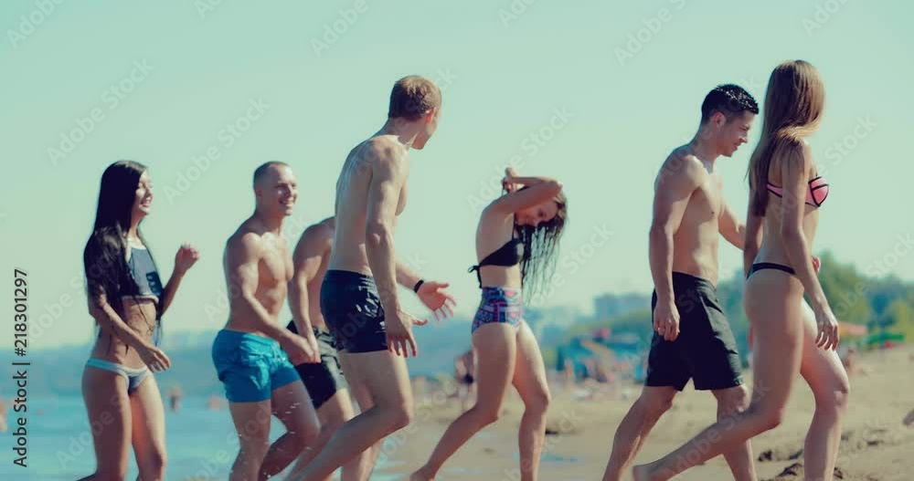 Group of friends coming out of the water on the beach. Side view Group of friends coming out of the water on the beach. Side view