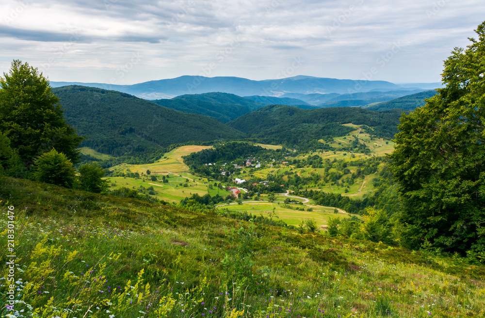 Obraz premium beautiful countryside landscape in mountains. forested hills and village down in the valley. overcast summer landscape