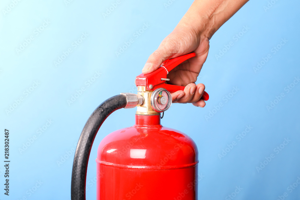 Hand holding fire extinguisher on blue background.