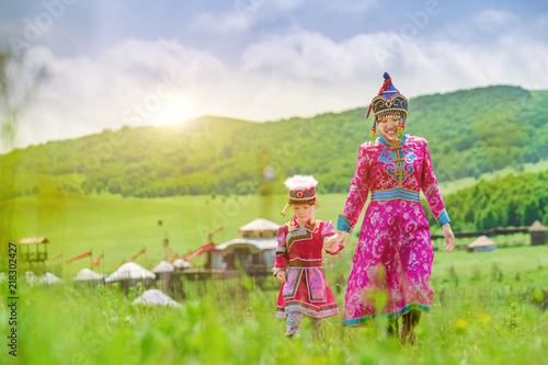 Mother and daughter wearing Mongolian costumes on the grassland