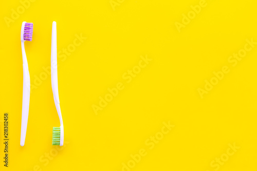 Oral hygeine. Toothbrushes on yellow background top view copy space