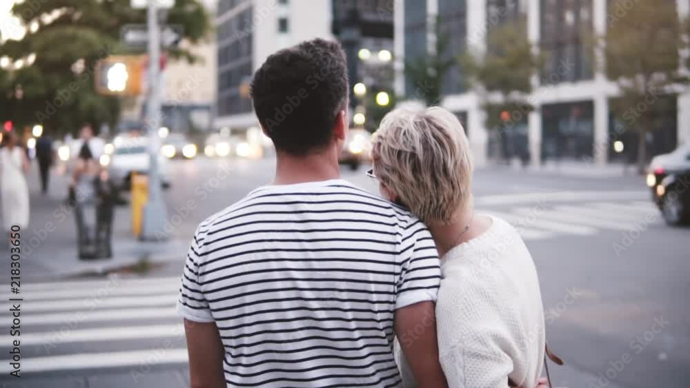 Slow motion smiling young Hispanic man hugging his Caucasian girlfriend near atmospheric New York summer street crossing Slow motion smiling young Hispanic man hugging his Caucasian girlfriend near atmospheric New York summer street crossing