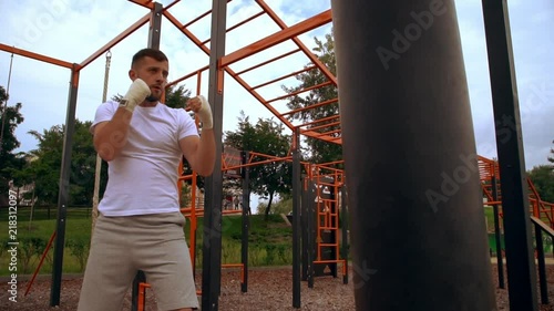 sportsman working out outdoor. male athlete punching the punchball. photo