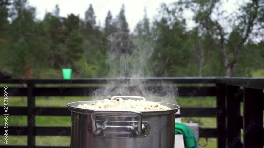 The steam is coming of a pot full of popcorn. The shot is taken at a cabin, so you can see the forest in the background. The steam is coming of a pot full of popcorn. The shot is taken at a cabin, so you can see the forest in the background.