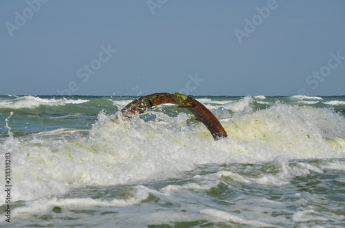 Stormy and tempestuous greeny waves of shattering in millions of sparkles into a sandy beach and into a stave of a sunken fisherman boat,  Krapetz camping beach, Durnakulak, Bulgaria, 08.2018 photo