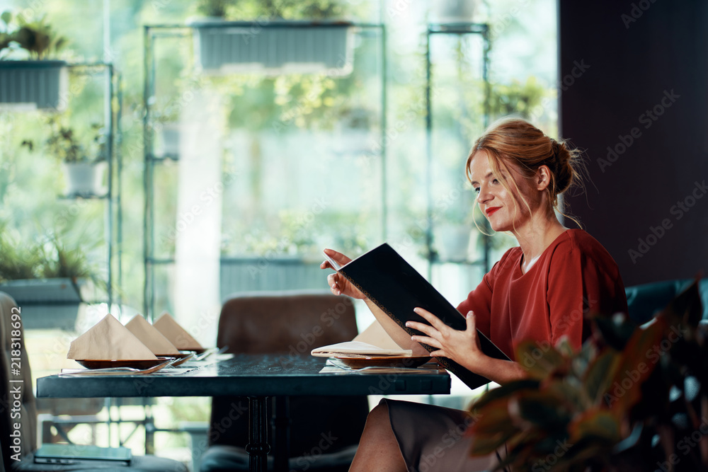 Elegant beautiful young woman reading menu at restaurant table Elegant beautiful young woman reading menu at restaurant table