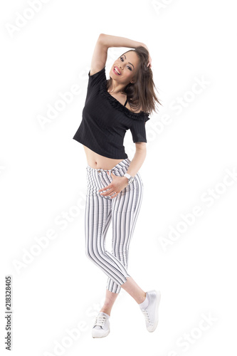 Carefree happy woman fashion model in striped pants and off shoulder top posing with hand in hair. Full body isolated on white background. 
