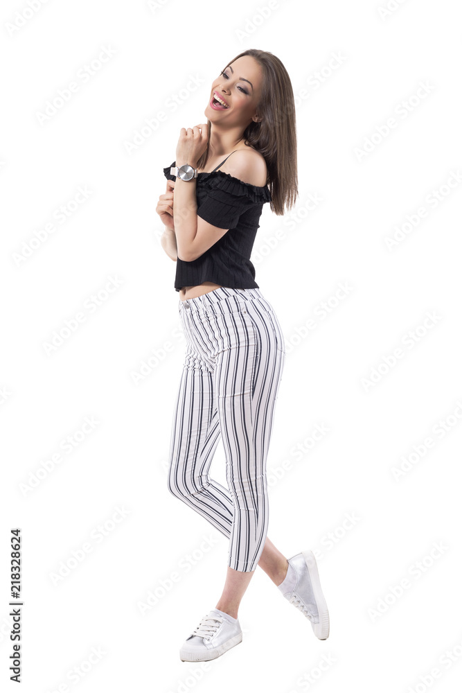 Carefree happy laughing young trendy woman in striped pants looking away. Side view. Full body isolated on white background. Carefree happy laughing young trendy woman in striped pants looking away. Side view. Full body isolated on white background.