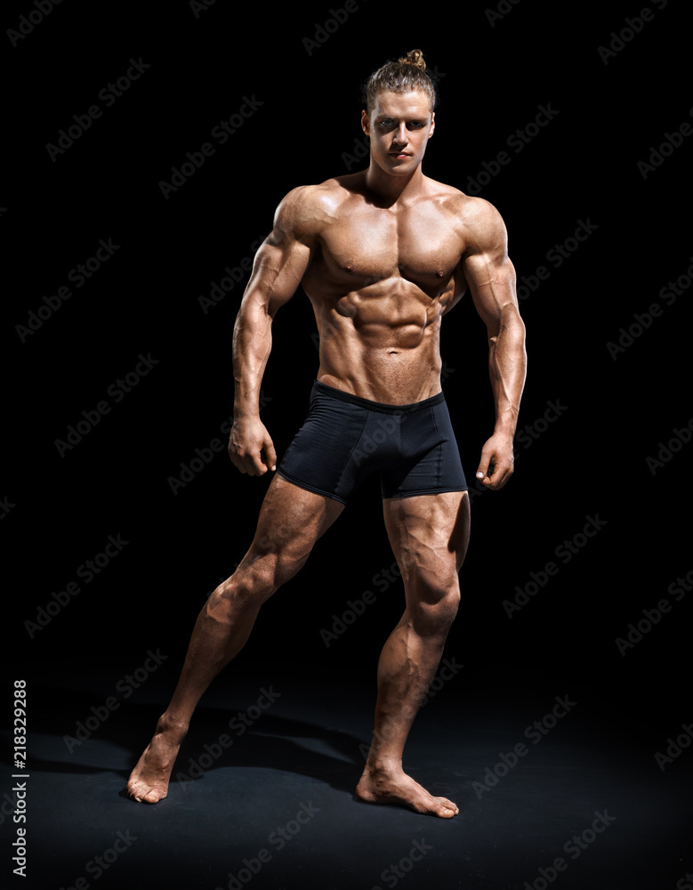 Athletic man posing. Photo of man with perfect physique on black background. Strength and motivation