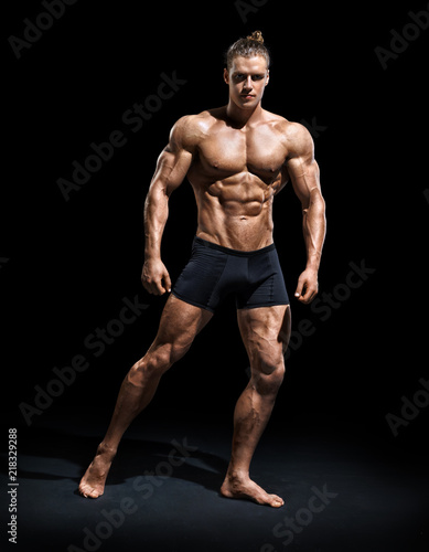 Athletic man posing. Photo of man with perfect physique on black background. Strength and motivation