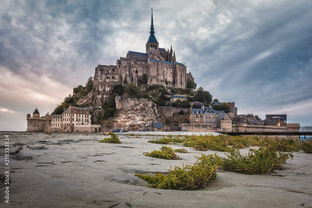 Beautiful view of famous historic Le Mont Saint-Michel tidal island with sandy and grass foreground, France