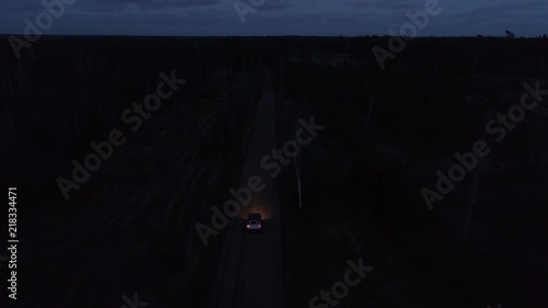 Aerial drone tracking shot of a 4x4 driving in night on a gravel road
